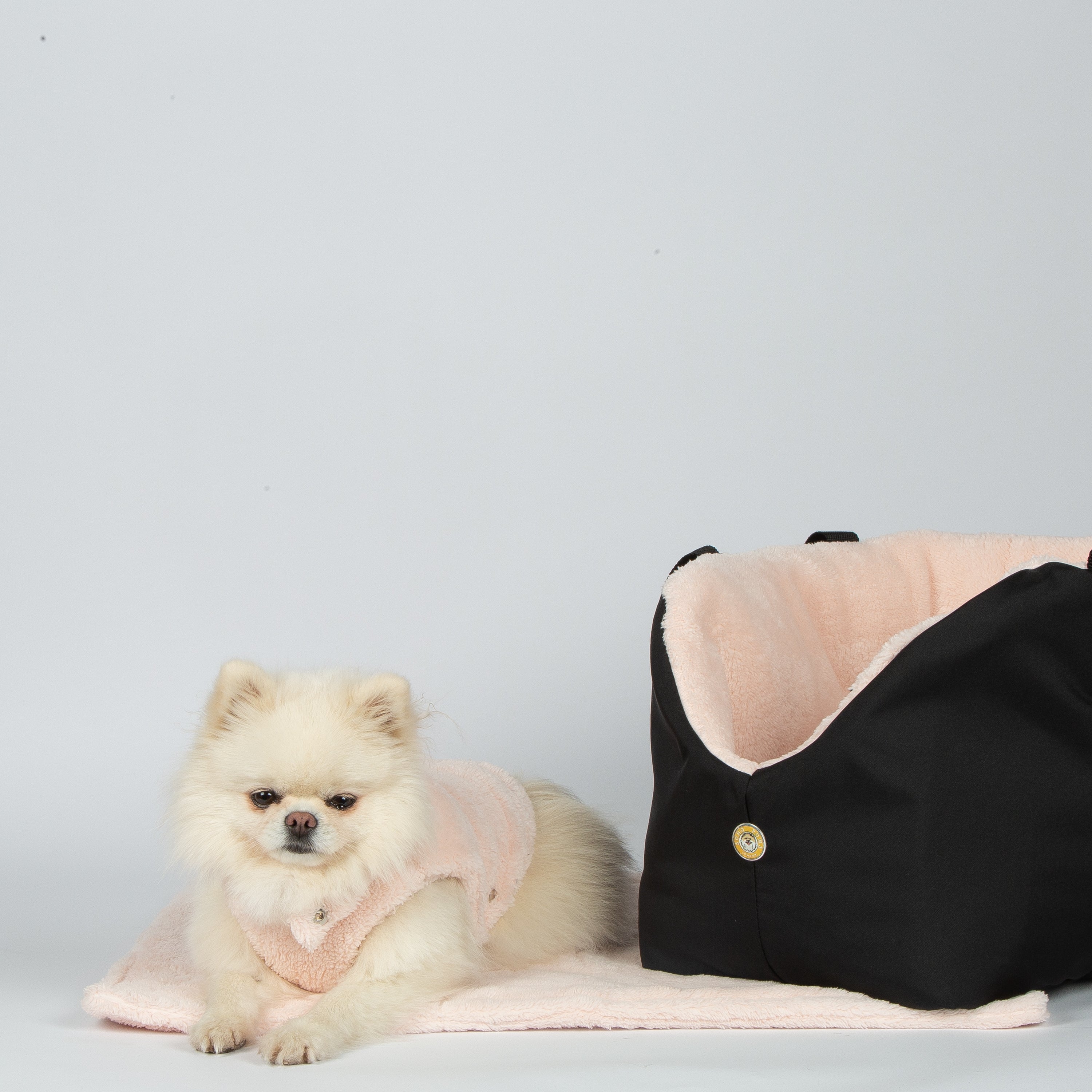 Pink teddy fleece dog blanket in carrier, draped around small dog