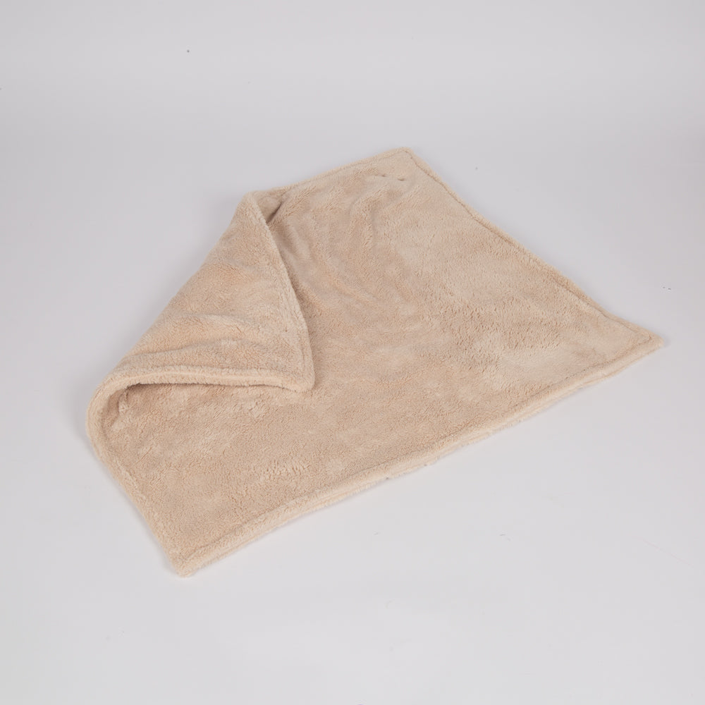 Beige plush dog blanket folded, soft textured surface
