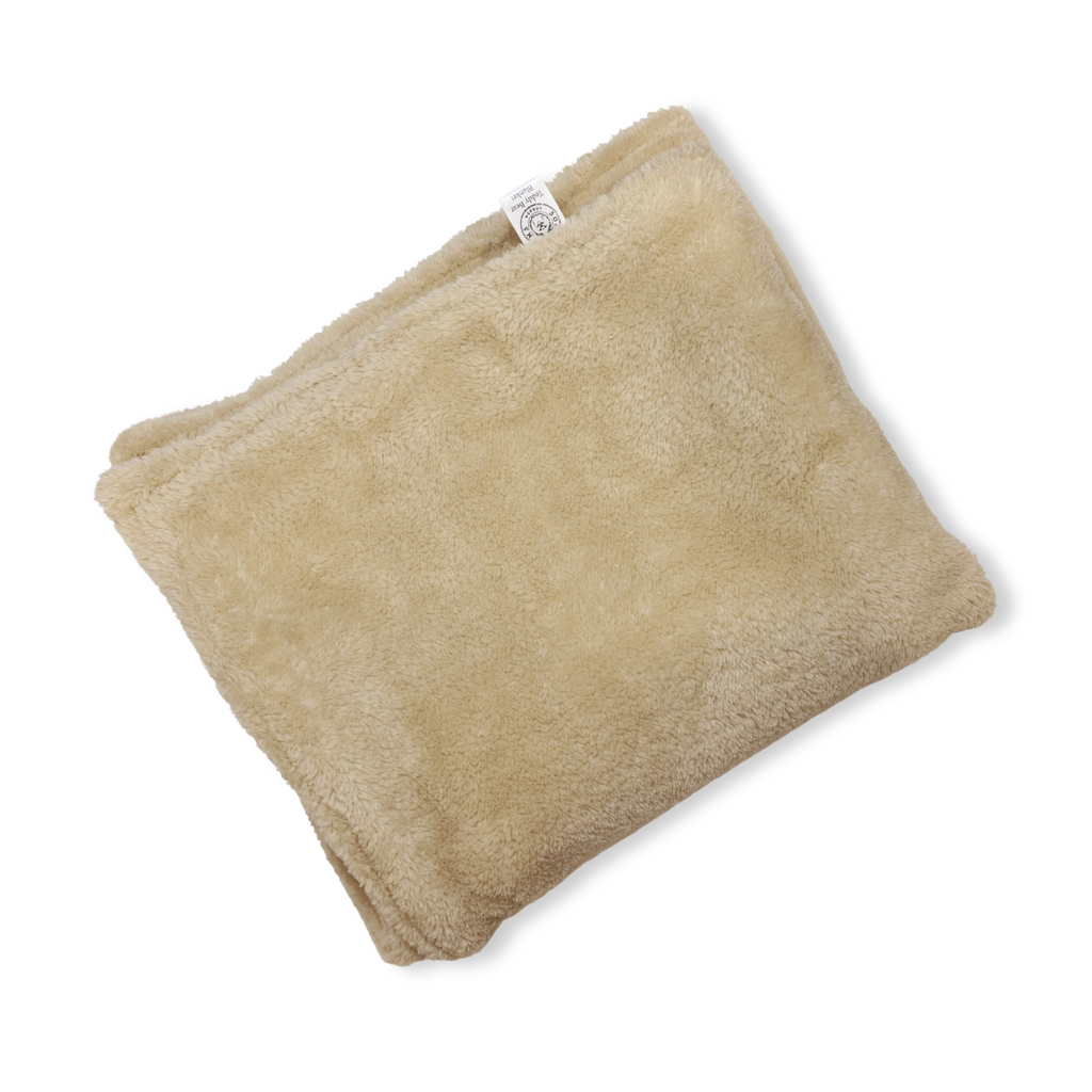 Beige plush dog blanket with sewn label on corner