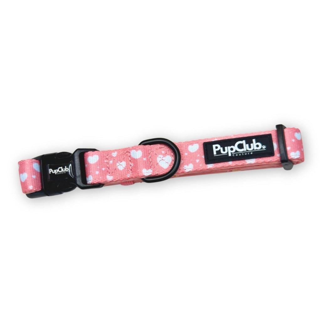 Pink dog collar with white heart pattern, black buckle and PupClub logo patch