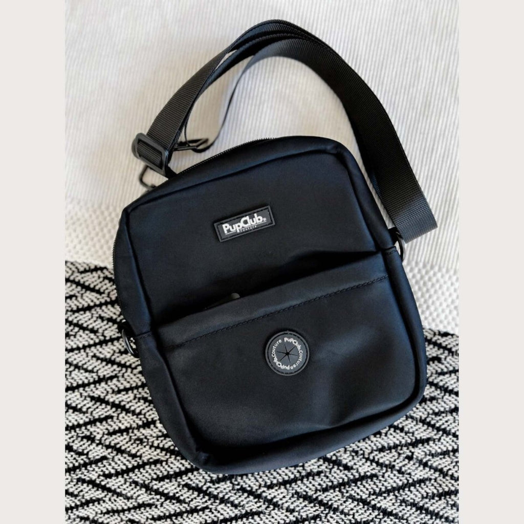 Black mini dog walking bag with adjustable shoulder strap and front logo patch