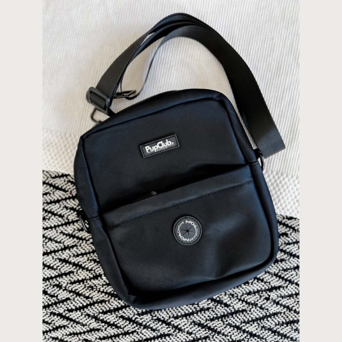 Black mini dog walking bag with adjustable shoulder strap and front logo patch