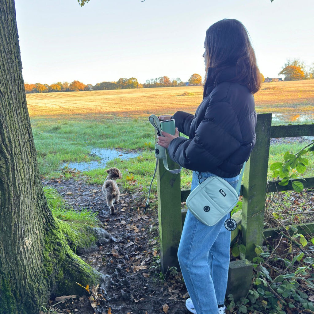 Mini dog walking bag in sage green, worn crossbody with adjustable strap