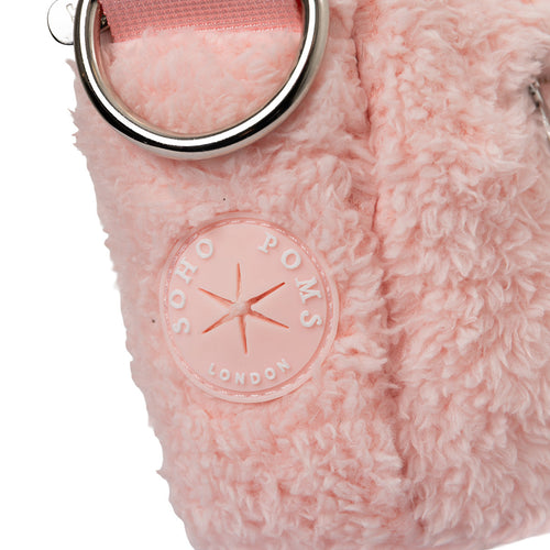 Blush pink faux-fur walking bag close-up with round logo badge and metal ring detail
